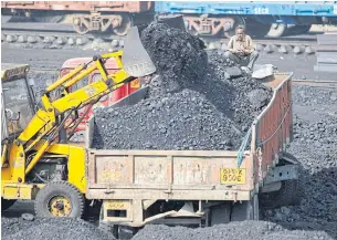  ?? REUTERS ?? A worker sits on a truck being loaded with coal at a railway coal yard on the outskirts of Ahmedabad, India.