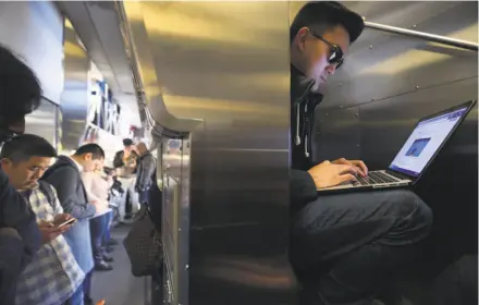  ?? Paul Chinn / The Chronicle ?? Edward Hu works on his laptop while sitting in a narrow staircase, and other passengers stand in the aisle while commuting northbound on Caltrain to San Francisco. This crowded situation is common as the trains are frequently filled beyond their...