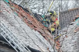  ??  ?? A firefighte­r works on the roof of the property in Snelsmore Common