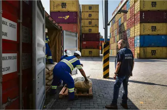  ?? Eduardo Knapp - 19. abr.18/Folhapress ?? Auditor da Receita Federal inspeciona container com sacas de café suspeito de ter drogas escondidas no porto de Santos