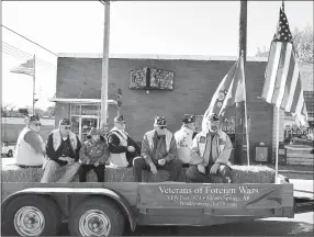  ?? Westside Eagle Observer/MIKE ECKELS ?? With the American Flag flying in the foreground and background, members of the Siloam Springs VFW Post 1674 ride on their float down Main Street during the fourth annual Decatur Veterans Day Parade Saturday.