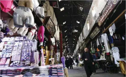  ?? — AFP ?? DAMASCUS: Syrians walk in the Midhat Pasha Souq in old Damascus yesterday.