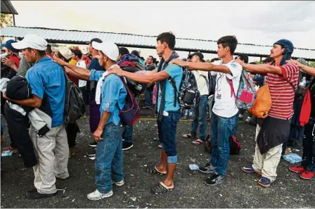  ?? — AFP ?? Human chain: Honduran migrants, who are taking part in a caravan heading to the US, waiting to cross the border from Ciudad Tecun Uman in Guatemala to Ciudad Hidalgo, Mexico.