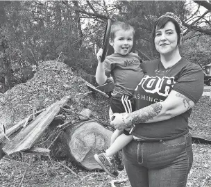  ??  ?? Lilly Langworth and her son Max stand last month in front of an oak tree felled by Hurricane Michael in the front yard of their Chipley, Fla., home. Langworth says she’s watching for signs of trauma among her three children following the storm.