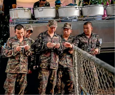  ?? GETTY IMAGES ?? Searchers take a lunch break at Tham Luang Nang Non cave where a a soccer team has gone missing in Chiang Rai, Thailand.