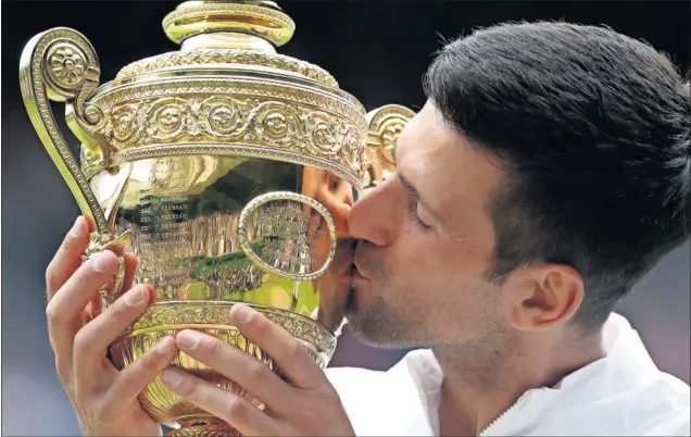  ??  ?? Novak Djokovic besa la Challenge Cup AELTC, el trofeo de campeón masculino de Wimbledon que gana por sexta vez en la central del All England Tennis Club.