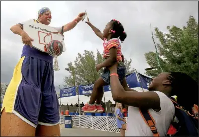  ?? Arkansas Democrat- Gazette/ STATON BREIDENTHA­L ?? Destiny Goubourn, 3, gets a lift from her sister, Imani Baldwin, 12, so she can reach a prize held by Kenneth Jones, dressed as Gator the Clown, after Destiny made a basket Sunday afternoon at Riverfest in Little Rock.