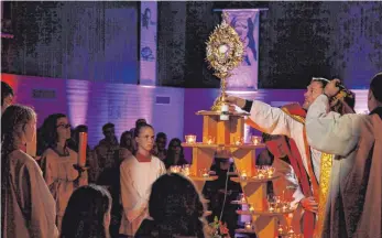  ?? FOTO: ULRICH GRESSER ?? Pfarrer Kilian Krug setzt das Allerheili­gste nach der Freitagabe­ndmesse zur Anbetung auf die Spitze der Pyramide mit Teelichter­n, die den brennenden Dornbusch symbolisie­rt.