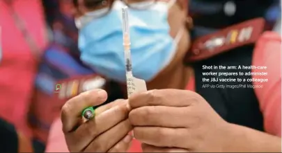  ?? The J&J vaccine to a colleague AFP via Getty Images/Phill Magakoe ?? Shot in the arm: A health-care worker prepares to administer