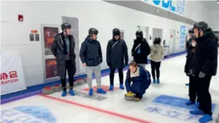  ?? ?? Students from Taiwan, China, try their hand at curling at the Ice Cube Ice Sports Center in Beijing on January 25