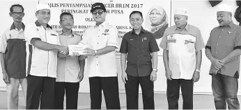  ??  ?? Razali (fourth left) hands over a BR1M voucher to a recipient at Beting Maro.