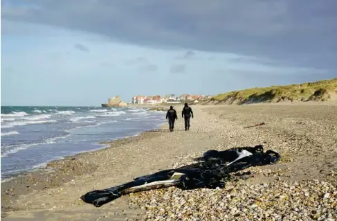  ?? (PA) ?? French po l ice officers pass a def l ated dinghy on the beach in Wimereux near Ca l ais