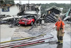  ?? The Sentinel-Record/RICHARD RASMUSSEN ?? Lake Hamilton Fire Department volunteer Jeremy Hill wraps up fire hoses Sunday morning after battling a blaze overnight at a resort on Lake Hamilton in Garland County.