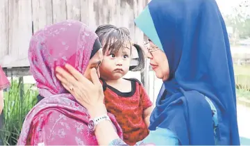  ??  ?? Fatimah (right) consoling a natural disaster victim in Kampung Medong Hilir, Dalat on Aug 10.