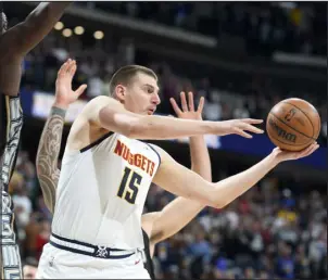  ?? DAVID ZALUBOWSKI — THE ASSOCIATED PRESS ?? Nuggets center Nikola Jokic, front right, passes the ball while Memphis Grizzlies center Steven Adams, back right, and forward Jaren Jackson Jr. defend in the first half Tuesday night at Ball Arena.