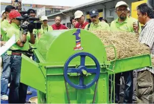  ??  ?? COOL MACHINE: Aziph (second from right) listening to innovator Siteo Akang (far right) of Keningau, Sabah as he explains his invention, the rice grain separating machine.