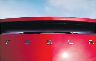  ??  ?? Sun shines off the rear deck of a roadster on a Tesla dealer's lot in the south Denver suburb of Littleton, Colorado. Tesla stock sank on reports that the company asked suppliers for refunds.