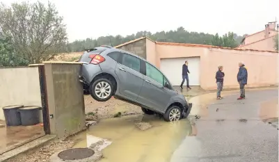  ?? — Gambar AFP ?? PENDUDUK berdiri dekat kereta yang dihanyutka­n oleh banjir kilat di selatan Perancis kelmarin.