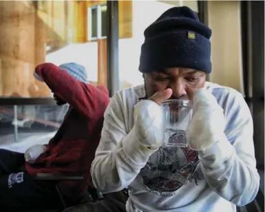  ?? ROBERT GAUTHIER/LOS ANGELES TIMES/TRIBUNE NEWS SERVICE ?? Razak Iyal, 35, carefully drinks water using hands that were severely frostbitte­n during an hours-long trek in the snow to cross the border from the U.S. into Manitoba on Christmas Eve. He had all of his fingers amputated.