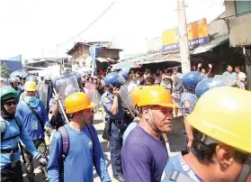  ?? SUNSTAR FOTO / ALLAN CUIZON ?? DEMOLITION. Police and a demolition team from the Mandaue City Government gather near the site in Barangay Mantuyong to maintain peace and order. The City wants to clear the area for the constructi­on of a road network leading to the ongoing site...