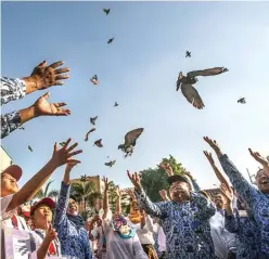  ?? GHOFUUR EKA/JAWA POS ?? TERBANGLAH TINGGI: Guru, murid, dan orang tua bersama-sama melepaskan burung di lapangan SMPN 3 Surabaya sebagai simbol untuk membebaska­n cita-cita.