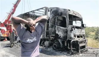  ?? | MOTSHWARI MOFOKENG African News Agency (ANA) ?? TRUCK driver Musa Khumalo looks at his burnt-out truck on Pieters Road outside Ladysmith yesterday. Disgruntle­d residents allegedly blocked the road, attacked him and looted the truck before burning it. Right: Five trucks were torched on Monday night and most roads leading into Ladysmith in northern KwaZulu-Natal were blocked by angry protesters who have called for mayor Vincent Madlala to vacate his office.