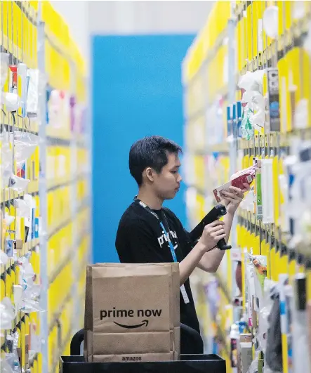  ?? JOSEPH NAIR/THE ASSOCIATED PRESS ?? An employee scans a product at the new Amazon Prime Now express delivery facility in Singapore on Thursday. Amazon’s e-commerce dominance in the U.S. is attributed in large part to the Amazon Prime service, which includes delivery discounts, music and...