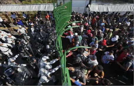  ?? MARCO UGARTE — THE ASSOCIATED PRESS ?? Migrants charge Mexican national guardsmen Saturday at the border crossing between Guatemala and Mexico in Tecun Uman, Guatemala. More than a thousand Central American migrants hoping to reach the United States surged onto the bridge spanning the Suchiate River that marks the border between both countries.
