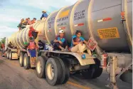  ?? PHOTO CREDIT ?? A woman holding her baby hitches a ride on the fender of a tanker in Niltepec, Mexico, on Tuesday. The Mexican government has provided little help for the migrants.