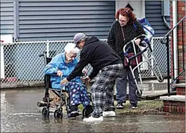  ?? SETH WENIG / AP ?? Two people help a woman in a wheelchair through a flooded street Wednesday in Lodi, N.J. States throughout the Northeast are facing severe weather conditions.