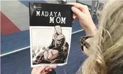  ??  ?? WASHINGTON: A woman looks at the cover of the comic book “Madaya Mom” on Oct 7, 2016. — AFP