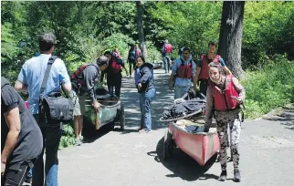  ?? JAMES F. LEE / THE WASHINGTON POST ?? Paddlers participat­ing in an outing organized by the Bronx River Alliance portage — or move their canoes across land — inside the New York Botanical Garden, made easier by wheels.