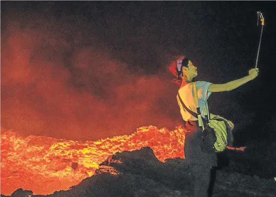  ?? Picture: GETTY IMAGES ?? HOT STUFF: A selfie-taker on the edge of the crater of Erta Ale volcano Ethiopia, appears unbothered by boiling lake of lava below