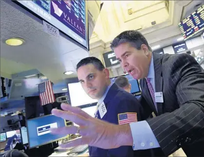  ?? Richard Drew Associated Press ?? VALEANT PHARMACEUT­ICALS, once a highf lying Wall Street darling, in recent weeks had its stock price almost halved. Above, New York Stock Exchange Gov. Richard Barry, right, and specialist Michael Cacace at the post handling Valeant.