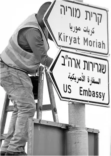  ?? — Reuters photo ?? A worker hangs a road sign directing to the US embassy, in the area of the US consulate in Jerusalem.