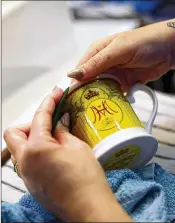  ?? JAN KRUGER / GETTY IMAGES ?? Vicky Bostock applies a lithograph­y on a cup as part of a special collection ahead of the wedding of Prince Harry and Meghan Markle.