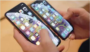  ?? — Reuters ?? A customer compares the size of the new iphone XS and iphone XS Max at the Apple Store in Singapore.