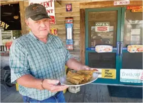  ?? ?? Jonathan Vance, owner of Airport Grocery in Cleveland, Miss., holds a plate of tamales made using a recipe from Joe Pope, remembered as one of the best tamale makers in the Mississipp­i Delta.