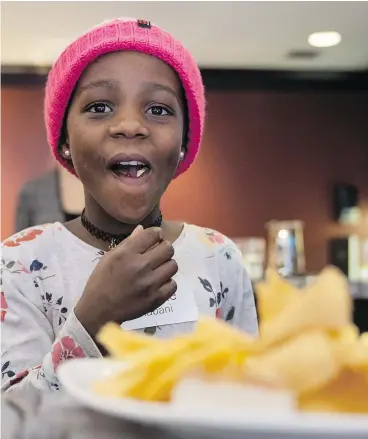  ?? RICHARD LAM ?? Sponsored refugee Nadette, 8, enjoys the buffet during a Canucks game. Giustra hosted refugees and their sponsor families at the game.