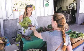  ??  ?? Emily Every, right, purchases beets from Carmon Taylor of Green Tractor Farm during Tuesday’s Santa Fe Farmers Market at the Railyard.