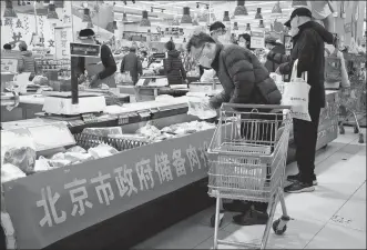  ?? NG HAN GUAN / AP ?? People shop for pork at a supermarke­t in Beijing on Saturday. The Beijing city government has been putting hundreds of tons of pork to market to maintain price stability.