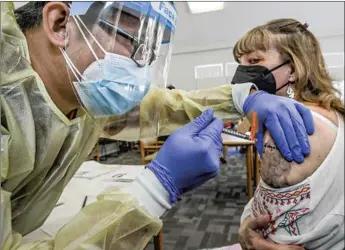  ?? Irfan Khan Los Angeles Times ?? REGISTERED NURSE Bryan Phan, left, administer­s the Johnson & Johnson COVID-19 vaccine to Linda Davis at a clinic on Wednesday at Whispering Fountains Senior Living Community in Lakewood.