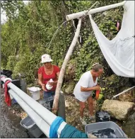  ?? DAVID SANTIAGO/MIAMI HERALD FILE PHOTOGRAPH ?? Utuado residents Maria Mercado, left, and Maritza Collazo wash their clothes on the side of the PR-10 road in Utuado during the aftermath of Hurricane Maria on Oct. 27 in Puerto Rico.