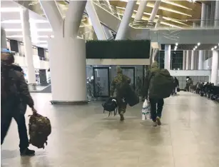  ?? (Reuters) ?? UNIDENTIFI­ED MEN carrying camouflage kitbags and Damascus airport duty-free bags arrive from Syria at Rostov Airport in Russia in January.