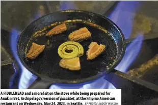  ?? AP PHOTO/LINDSEY WASSON ?? A FIDDLEHEAD and a morel sit on the stove while being prepared for Anak ni Bet, Archipelag­o’s version of pinakbet, at the Filipino American restaurant on Wednesday, May 24, 2023, in Seattle.