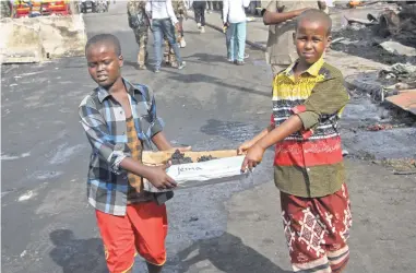  ?? AP ?? Somali children assist other civilians and security forces in their rescue efforts by carrying away unidentifi­ed charred human remains in a cardboard box to clear the scene of Saturday’s blast in Mogadishu, Somalia, yesterday. The death toll from the...