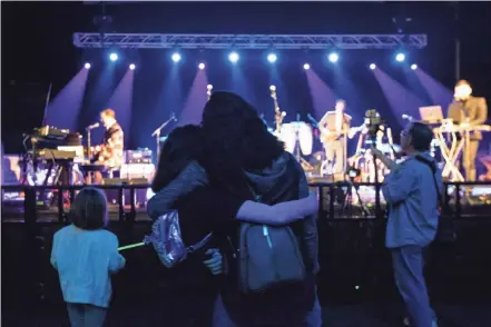  ?? PHOTOS BY NICOLAS GALINDO/COLUMBUS DISPATCH ?? Spectators hug during the Sgt. Peppercorn’s marathon performanc­e of the musical catalogue of the Beatles at The Athenaeum Theater on Saturday. The band consists of various local artists who switch in and out of songs throughout the day.