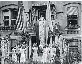  ?? THE CROWLEY COMPANY/LIBRARY OF CONGRESS ?? In this photo from Aug. 19, 1920, Alice Paul, chair of the National Woman’s Party, unfurls a banner at party headquarte­rs in Washington after ratificati­on of the 19th Amendment.