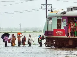  ?? — PTI ?? Commuters stranded on their way to Mumbai as a section of Western Raillway remain suspended due to waterloggi­ng on tracks after heavy rainfall at Nallasopar­a area in Mumbai on Wednesday.