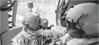  ??  ?? U.S. National Guard Staff Sgt. Lawrence Lind, left, and Sgt. Ray Smith hoist a rescued boy into a Black Hawk helicopter Wednesday in Port Arthur, Texas.